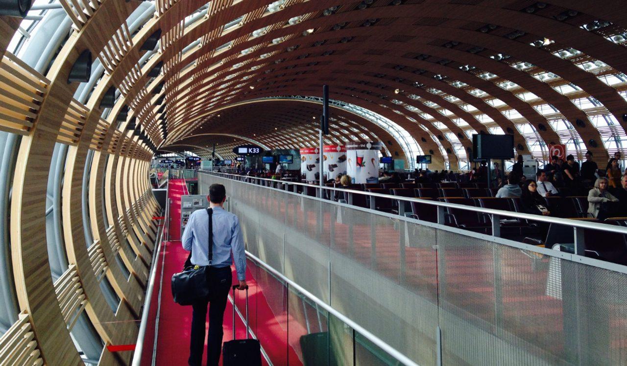 La passerelle tubulaire en bois du Terminal 2E de Roissy CDG, avec un voyageur et sa valise.